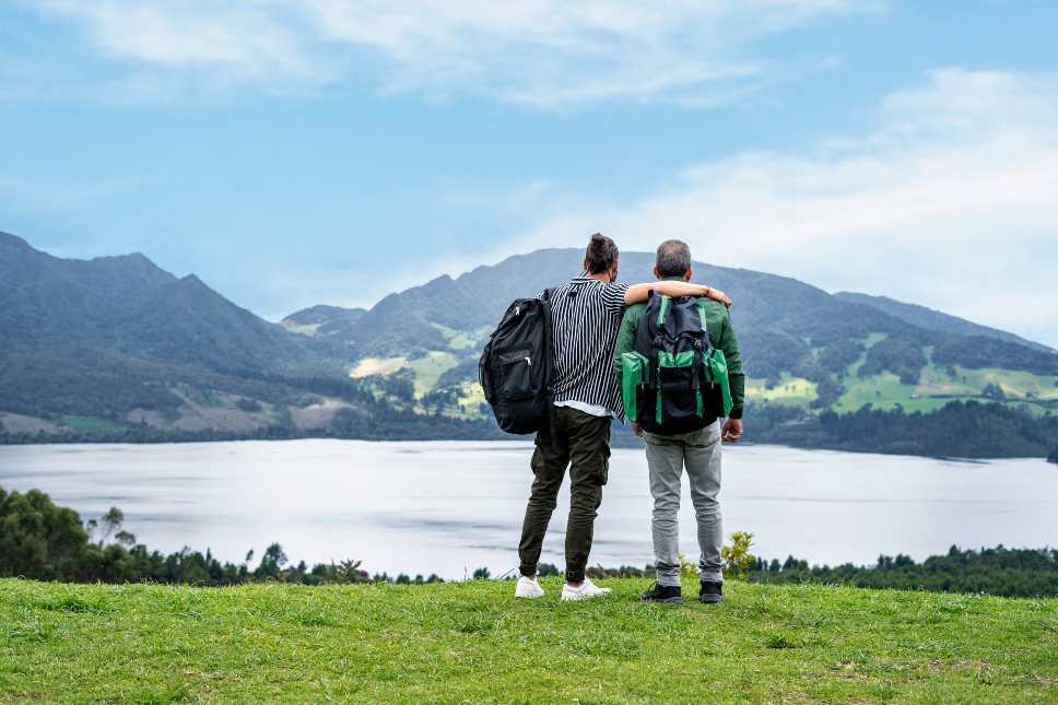 Hombres cargando mochilas y al fondo una montaña y un lago de día Foto GettyImages