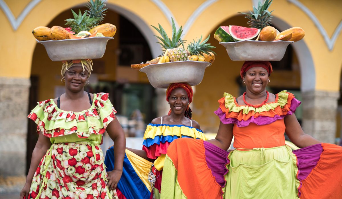 Happy group of women selling fruits in Cartagena and looking at the camera smiling - travel like a local