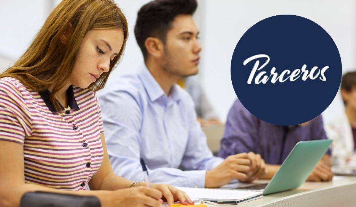 Jóvenes estudiando en una clase mientras usan un computador