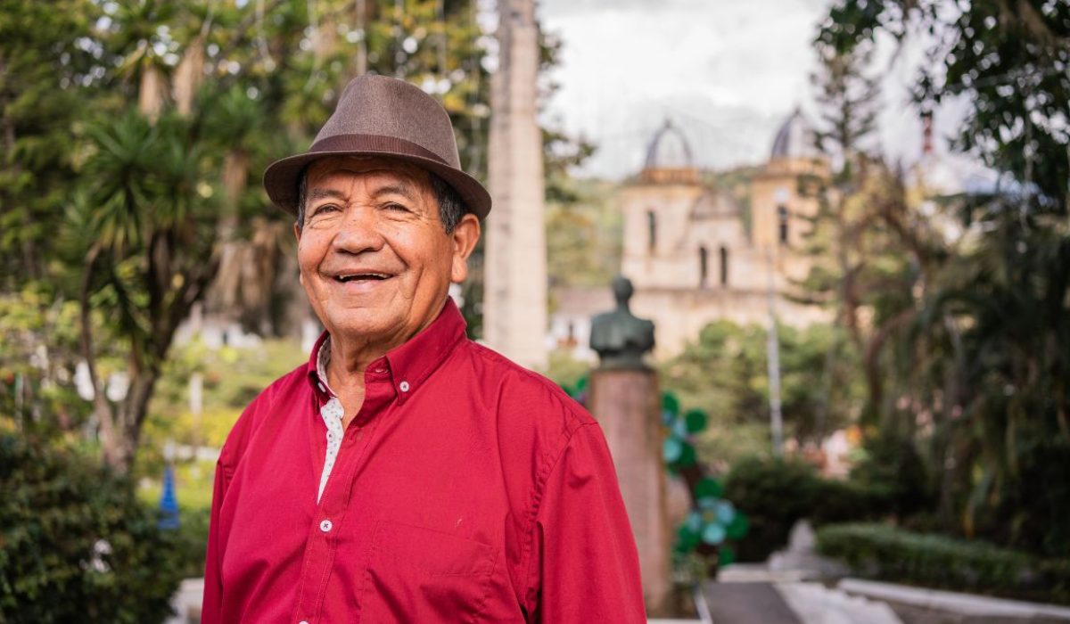 Hombre de edad avanzada, riendo y de fondo un paisaje de Boyacá.